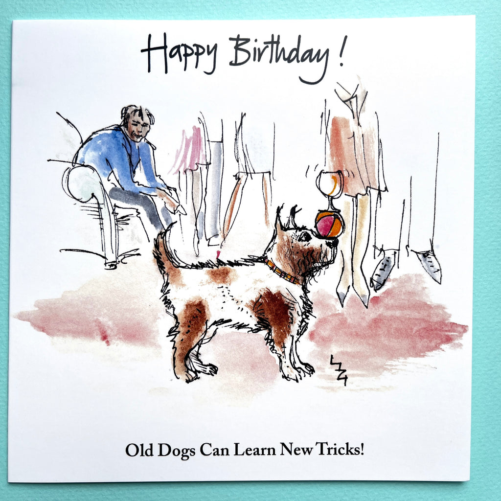 Birthday card with a small scruffy dog juggling a ball and glass on nose and people at a party, featuring the text 'Happy Birthday! Old Dogs Can Learn New Tricks!'.