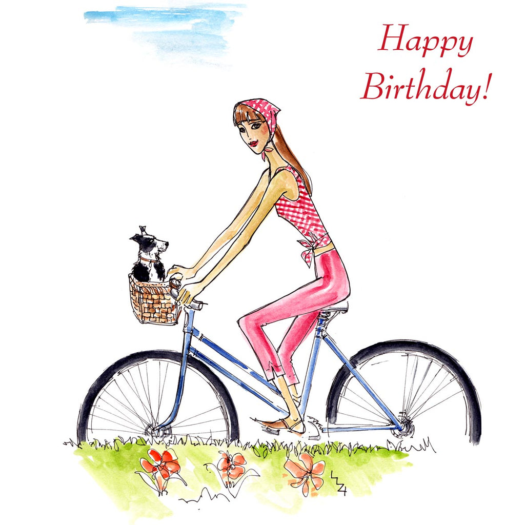 A carefree young girl is riding her bike in the countryside with her black & white patched puppy in the front basket. Caption reads 'HappyBirthday!'